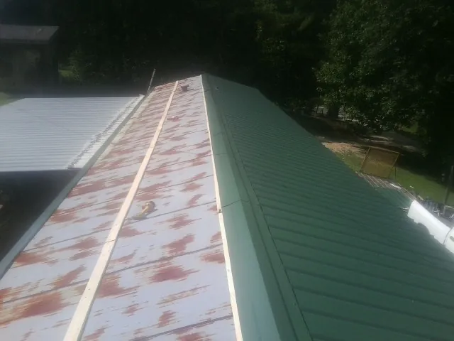 Old rusted panels beside newly installed green metal roofing — Wind Damage Roof Repair by Roofing Brothers in Hyde Park