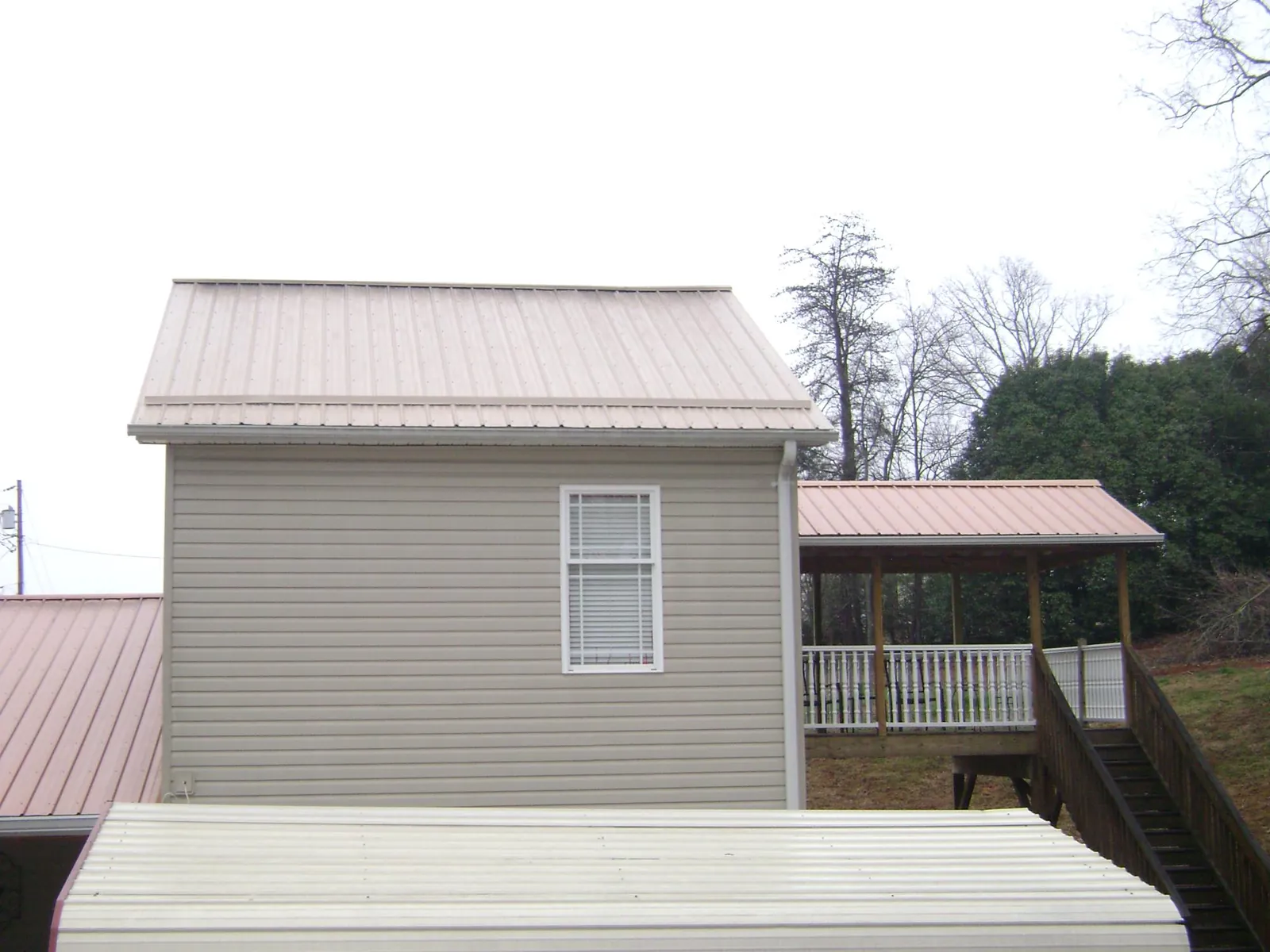 Tan metal roofs on a two story addition and attached porch, from a Roof Replacement job in Hyde Park